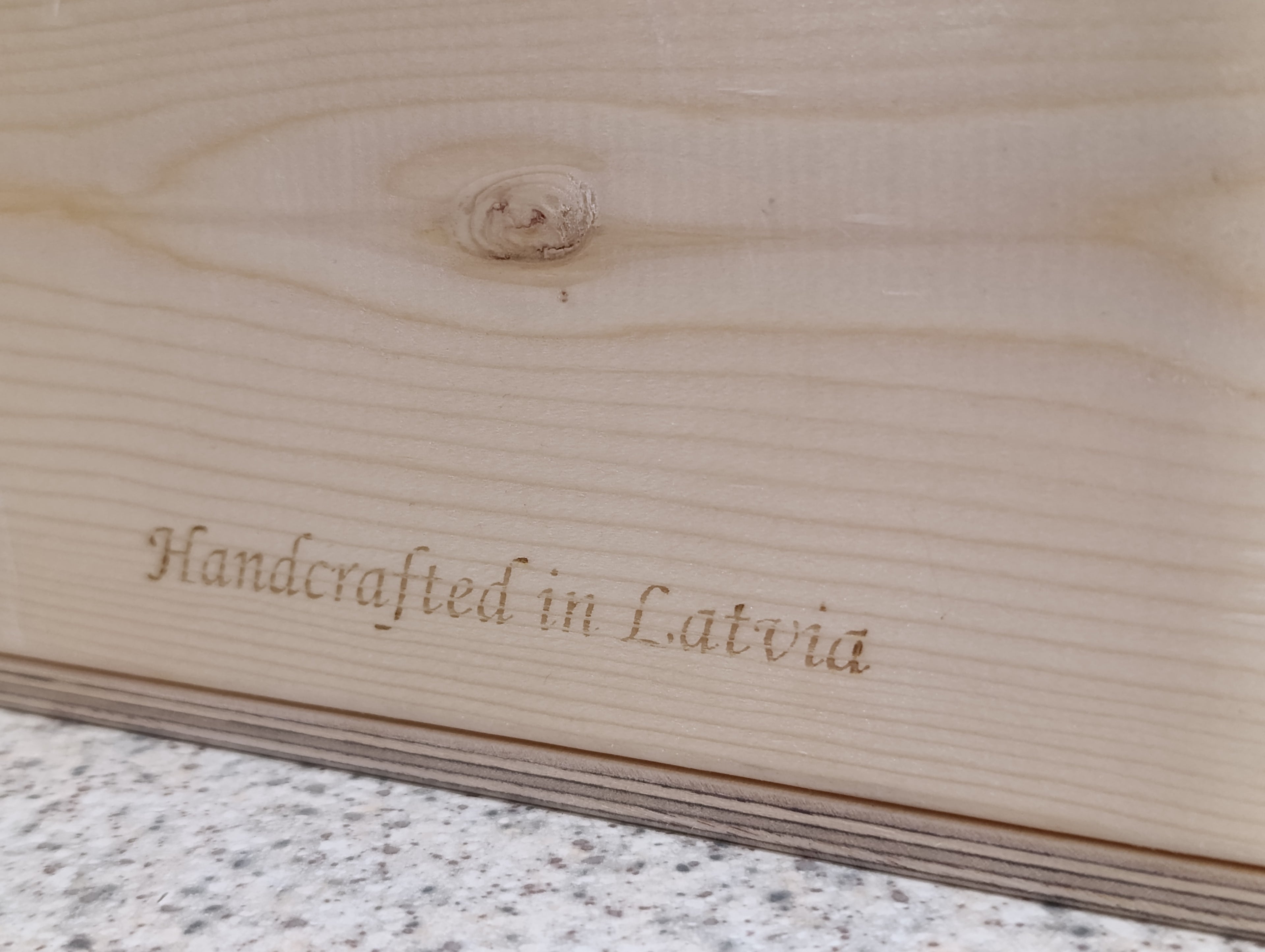 Wooden surface with 'Handcrafted in Latvia' engraving