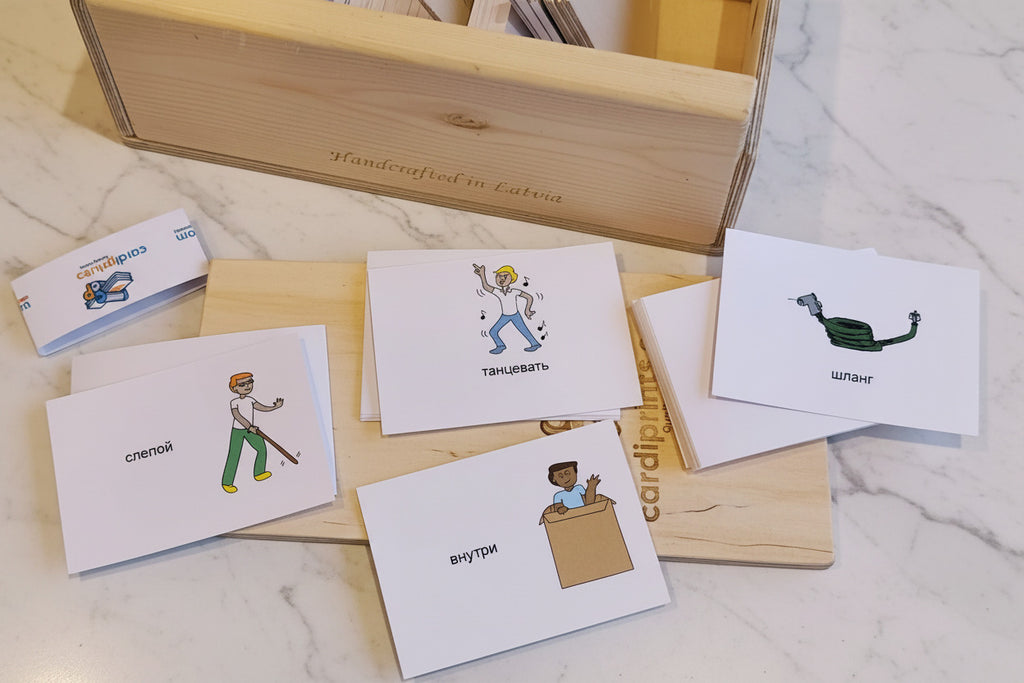 Set of flash cards with illustrations and text on a marble surface with a wooden box.
