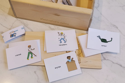 Set of flash cards with illustrations and text on a marble surface with a wooden box.