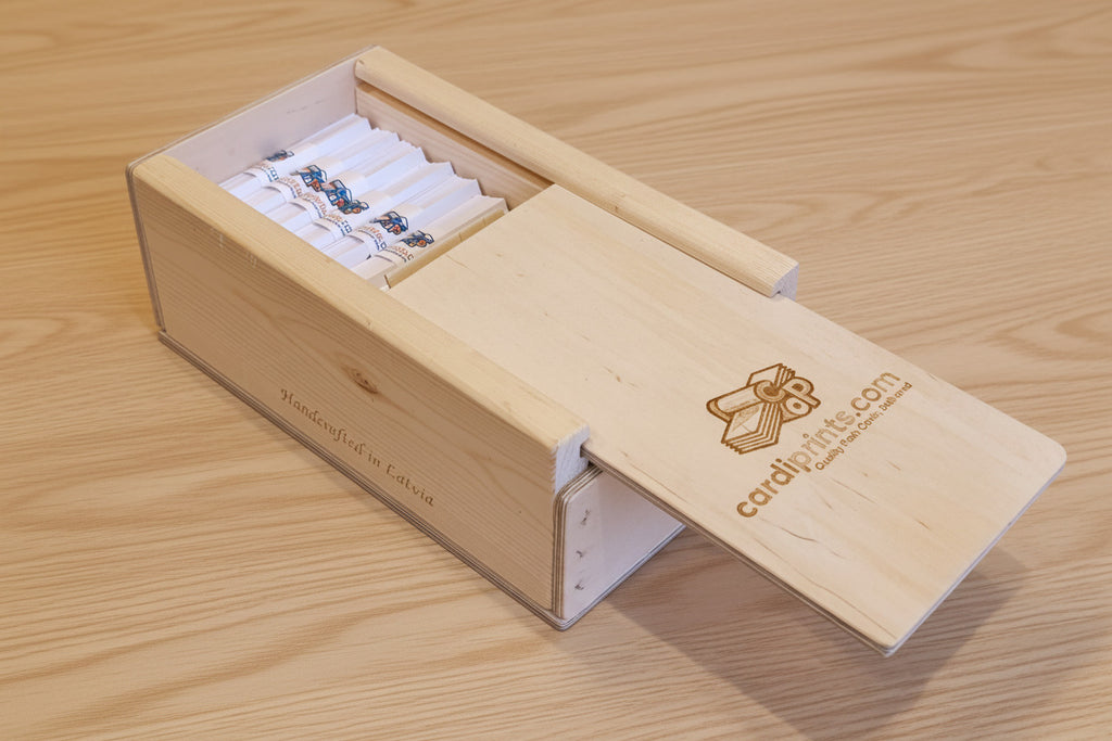 Wooden box with a lid open, displaying cards inside on a textured surface.
